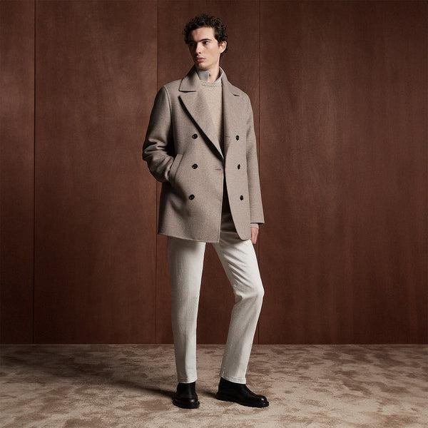 Taupe double-breasted outerwear styled against a rich brown wall